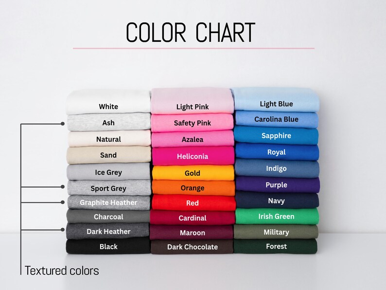 May include: A color chart displaying three vertical stacks of folded fabric in various shades. The labels include White, Ash, Natural, Sand, Ice Grey, Sport Grey, Graphite Heather, Charcoal, Dark Heather, Black, Light Pink, Safety Pink, Azalea, Heliconia, Gold, Orange, Red, Cardinal, Maroon, Dark Chocolate, Light Blue, Carolina Blue, Sapphire, Royal, Indigo, Purple, Navy, Irish Green, Military, and Forest.