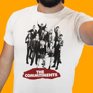 May include: White t-shirt with a black and white image of a group of people, with the text "THE COMMITMENTS" in red.
