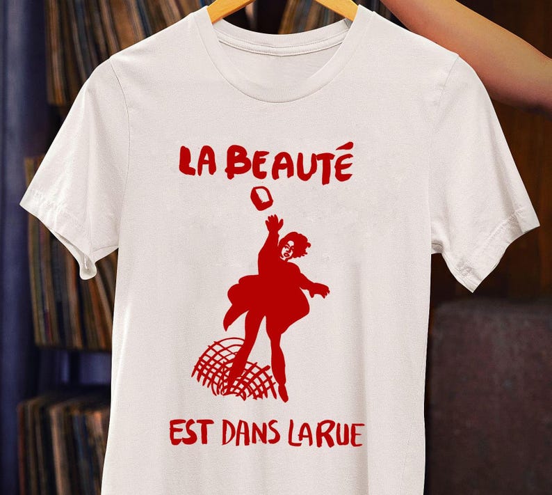 Customized white T-shirt from La Beauté est dans la rue hanging on a hanger