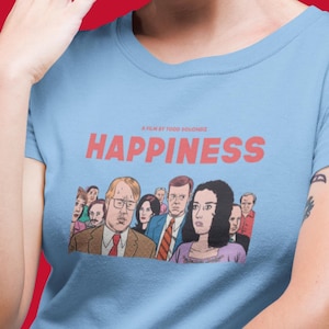 May include: A light blue t-shirt with a red graphic of the movie "Happiness" by Todd Solondz. The graphic features a group of cartoon characters, including a man with glasses and a woman with long dark hair.