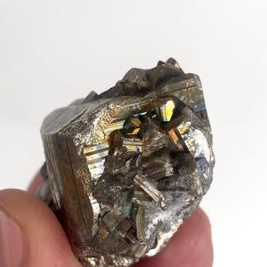May include: A cluster of iridescent pyrite crystals with a metallic gold and brown colour. The crystals are arranged in a rough, natural shape.