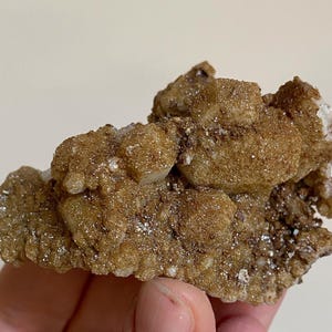 Könnte beinhalten: Ein Cluster aus braunen und weißen Calcitkristallen mit einer rauen, strukturierten Oberfläche. Die Kristalle sind in einer natürlichen Formation zusammengefügt.