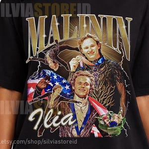 May include: Black t-shirt featuring a graphic of Ilia Malinin with the text "MALININ" in gold. The graphic includes images of Ilia Malinin with a medal and the American flag. The Etsy shop name "silviastoreid" is also visible.