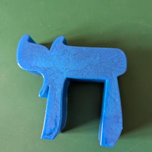 May include: A blue plastic sculpture of the Hebrew letter 'Chai', which means 'life' in Hebrew.