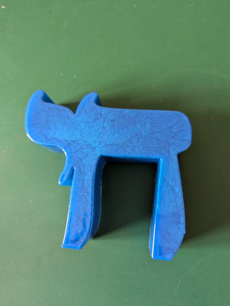 May include: A blue plastic sculpture of the Hebrew letter 'Chai', which means 'life' in Hebrew.