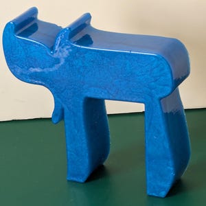 May include: A blue ceramic sculpture of the Hebrew letter 'Chai', which means 'life' in Hebrew. The sculpture is made of a smooth, glossy ceramic and has a slightly textured surface.