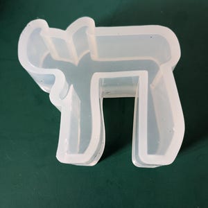 May include: A white silicone mold shaped like the Hebrew letter 'Chai'.