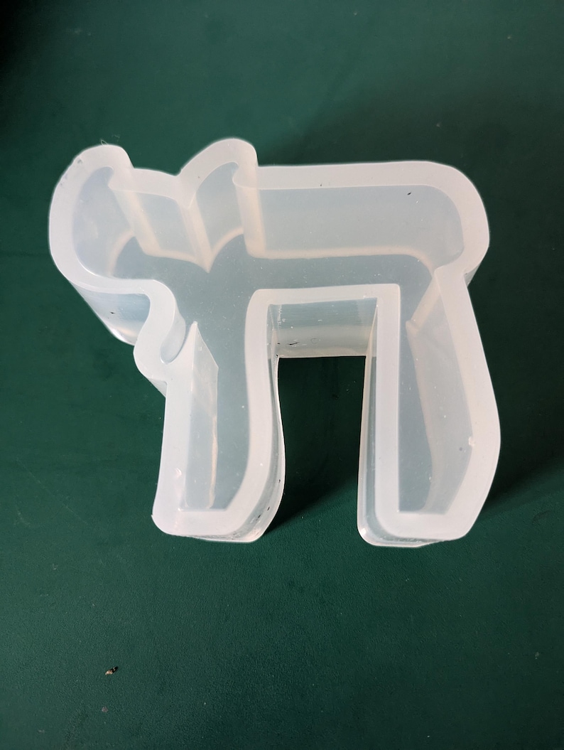 May include: A white silicone mold shaped like the Hebrew letter 'Chai'.