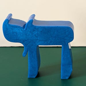 May include: A blue, three-dimensional, plastic sculpture of the Hebrew letter 'Chai' which means 'life' in Hebrew.