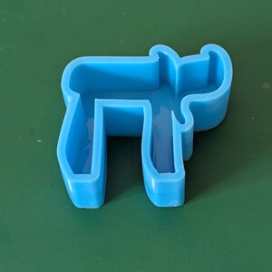 May include: A light blue plastic mold shaped like a reindeer. The mold is hollow and has a smooth surface.