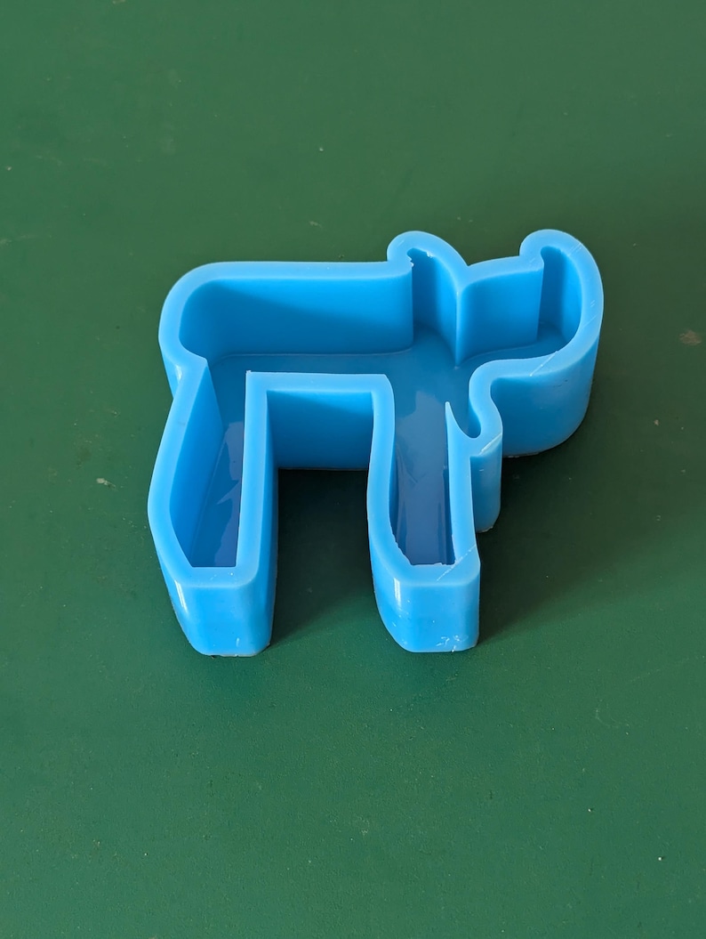 May include: A light blue plastic mold shaped like a reindeer. The mold is hollow and has a smooth surface.