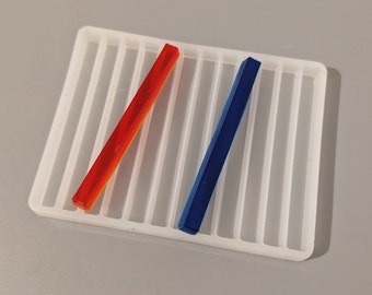 May include: A white silicone mold with 12 rectangular slots. Two resin sticks, one red and one blue, are placed in the mold.