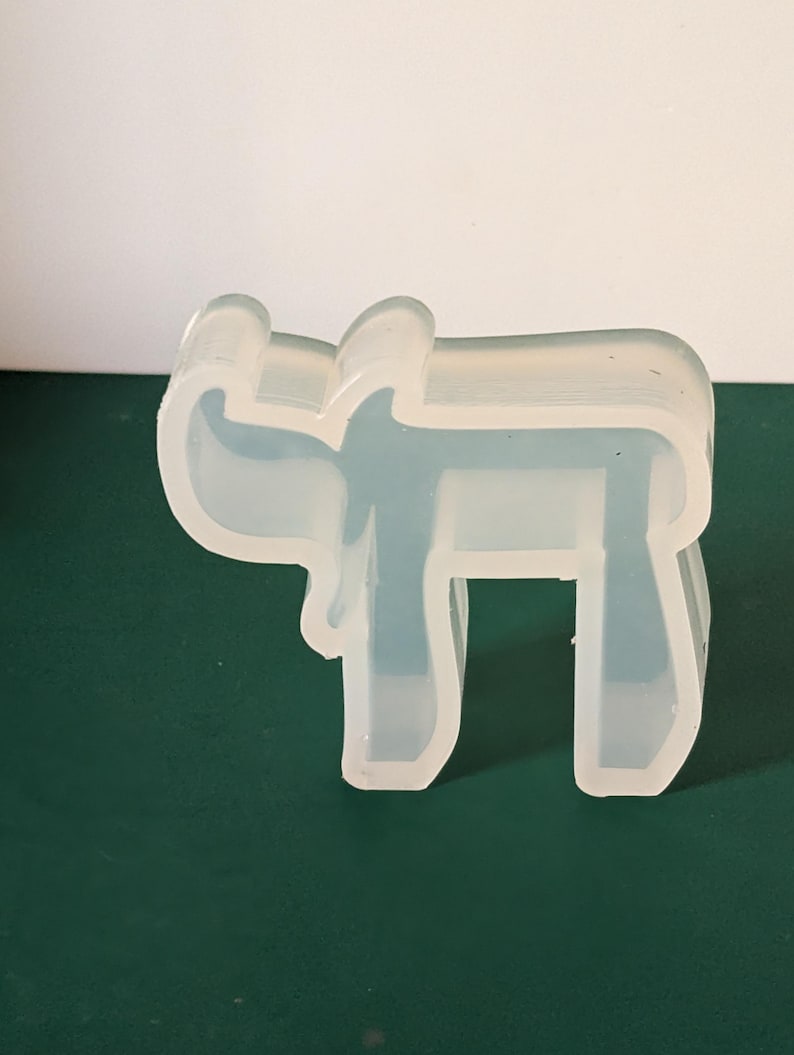 May include: A clear silicone mold shaped like the Hebrew letter 'Chai'.