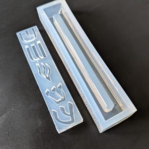 May include: Two clear silicone moulds for making candles. One mould is a rectangular shape with a raised design of the Hebrew word "Chai" which means "life". The other mould is a long, thin rectangle.