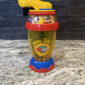 May include: A yellow and red plastic shaker with a blue handle and a McKids logo. The shaker has a clear plastic container with a yellow lid and a blue and red base. The shaker has a picture of the McKids characters on the side.