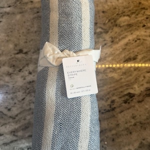 May include: Rolled blue and white striped throw blanket tied with a white ribbon. The tag reads "Everywhere Stripe Throw" and "Mindfully Made". The blanket measures 50 x 60 inches (127 x 152 cm).