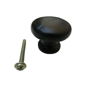 May include: A black cabinet knob with a rounded top and a short stem. A silver screw with a slotted head is next to the knob. The knob is likely made of wood or a similar material.