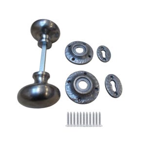 Könnte beinhalten: Antik-Türbeschlagsatz mit dunklem, metallischem Finish. Das Set enthält zwei ovale Türknöpfe, zwei kreisförmige Rückplatten, zwei Schlüssellochabdeckungen und einen Satz silberner Schrauben. Die Hardware hat eine gehämmerten Textur.