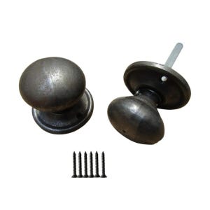 Könnte beinhalten: Zwei Türknöpfe im antiken Stil mit dunkler, verwitterter Oberfläche. Die Knöpfe sind rund mit flachem Sockel und werden mit passenden Schrauben geliefert. Die Hardware hat eine Vintage-Ästhetik, passend für Innenarchitekturprojekte.