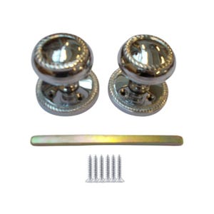 Könnte beinhalten: Zwei polierte Türknöpfe aus Chrom mit einem Seildesign an den Rändern. Eine lange, dünne, goldfarbene Metallstange und fünf silberne Schrauben sind ebenfalls enthalten. Die Knöpfe sind rund und glänzend.