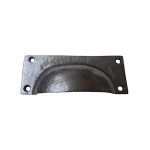 May include: A dark gray, cast iron cup pull with a rectangular backplate. The pull has a semi-circular handle and four screw holes for mounting. The finish has a textured, rustic appearance, suitable for cabinets or drawers.