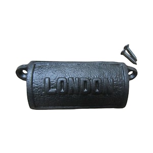 Puede incluir: Un tirador de puerta de hierro fundido negro con la palabra "LONDON" grabada en la parte delantera. Se incluyen dos tornillos. El tirador tiene una superficie texturizada y una forma rectangular con extremos redondeados.