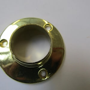 Könnte beinhalten: Ein glänzender, goldfarbener Metallflansch mit kreisförmiger Basis und zylindrischer Öffnung. Er hat drei gleichmäßig verteilte Schraubenlöcher. Die Oberfläche reflektiert das Licht und betont die polierte Oberfläche. Durchmesser ca. 6 cm.