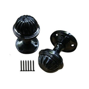 Può includere: Due pomelli per porte neri con un design arrotondato e scanalato. I pomelli hanno una base circolare e sono accompagnati da diverse viti nere. L'hardware è posto su uno sfondo bianco.