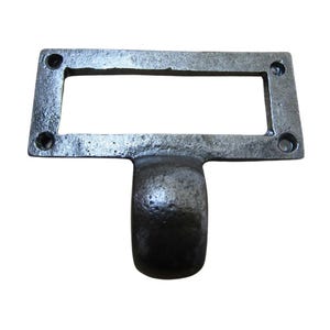 Puede incluir: Un tirador de cajón rectangular gris oscuro con un asa. El tirador tiene una abertura rectangular en el centro y cuatro orificios para tornillos en las esquinas. El asa tiene forma cilíndrica redondeada.