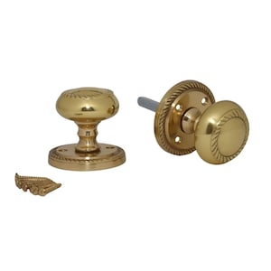 May include: Two brass door knobs with a rope design. One is attached to a round plate with screw holes, the other is a standalone knob. A small pile of screws is also included. The knobs are made of brass.