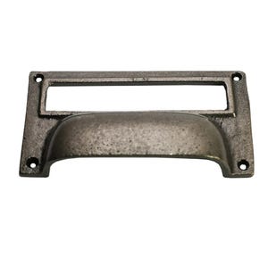 Puede incluir: Un tirador de cajón de metal gris oscuro envejecido, con un portaetiquetas rectangular y un asa curvada. El herraje tiene un acabado envejecido y cuatro orificios para tornillos para el montaje. Este tirador de estilo vintage es adecuado para armarios y cajones.