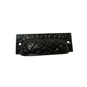 May include: A black, ornate drawer pull with a floral design. The pull is rectangular with a curved handle and two screw holes. The surface has a detailed, raised pattern of flowers and leaves.