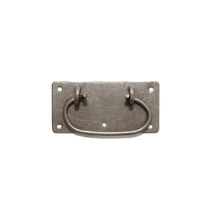 May include: A rectangular, antique-style drawer pull with a dark gray finish. The pull features a curved handle attached to a rectangular backplate with four screw holes. The hardware is made of metal.
