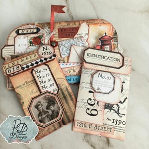 May include: A vintage-style mailbox-shaped paper craft with various labels and envelopes. The design includes the words "MAIL," "REMEMBER 618," and "IDENTIFICATION." The color palette features beige, brown, and red accents, with a small red flag.