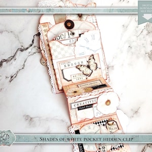 Puede incluir: Un clip de bolsillo hecho a mano con una estética vintage. El diseño presenta elementos de papel en capas en tonos blancos y melocotón, adornados con mariposas y flores. El texto incluye "YOU ARE ENOUGH" y "CREATIVITY".