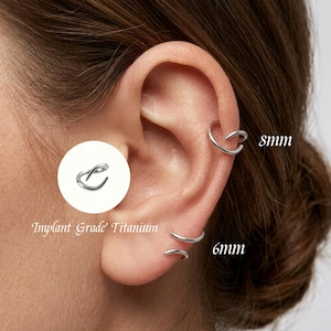 May include: A silver-coloured hoop earring made of implant grade titanium. The earring is shown in two sizes, 8mm and 6mm, worn in the ear cartilage and lobe. A circular inset highlights the smooth, continuous design of the metal hoop.