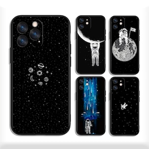 May include: A collection of black phone cases featuring space-themed designs. One case displays a starry sky with planets and moons. Other cases showcase astronauts, the moon, and shooting stars. The cases have a black border.