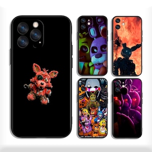 May include: A collection of black phone cases featuring various designs from the Five Nights at Freddy's franchise. The cases showcase characters like Foxy, Bonnie, and Springtrap, with vibrant colors and detailed graphics.