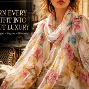 Puede incluir: Una mujer lleva una bufanda blanca con un estampado floral en rosa, azul y amarillo. La bufanda está drapeada alrededor del cuello y los hombros. La imagen incluye el texto "TURN EVERY OUTFIT INTO SOFT LUXURY" y las palabras "Lightweight, Elegant, Effortless."