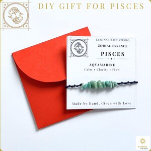 May include: A bracelet featuring light green tumbled aquamarine stones on a dark blue cord, attached to a white card labeled Lumina Craft Studio Zodiac Essence Pisces, resting on a bright red envelope with the text DIY GIFT FOR PISCES.