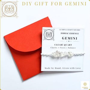 May include: A white card featuring the text LUMINA CRAFT STUDIO, ZODIAC ESSENCE, GEMINI, CLEARI QUART, Clarity, Focus, Balance, and Made by Hand, Given with Love, with a clear crystal chip bracelet attached, next to a bright red envelope.
