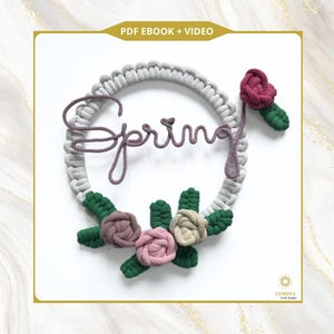 May include: A handmade macrame wreath with the word "Spring" in cursive script. The wreath is gray with attached fabric flowers in shades of pink, mauve, and beige, with green leaves. The top of the image has the text "PDF EBOOK + VIDEO".