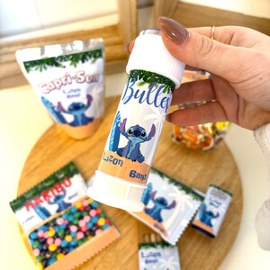 Peut inclure: Un produit cylindrique blanc et bleu avec le mot "Bullett" et une illustration de personnage de dessin animé. Plusieurs petits paquets et une pochette Capri-Sun avec le même personnage sont également visibles. Les articles sont disposés sur une surface en bois.