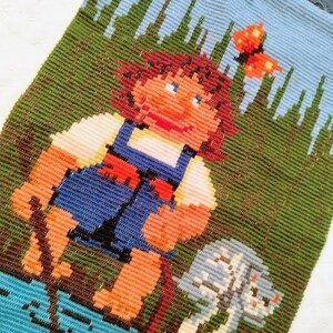 May include: A vintage needlepoint wall hanging featuring a girl with brown hair and a blue dress standing in a green field with a white dog. A butterfly with orange wings is flying above the girl's head.