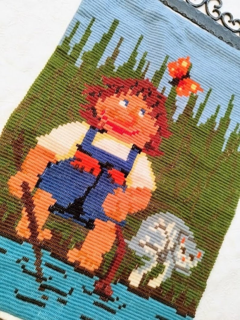 May include: A vintage needlepoint wall hanging featuring a girl with brown hair and a blue dress standing in a green field with a white dog. A butterfly with orange wings is flying above the girl's head.