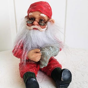 Scandinavische kerstkabouter zit een sok te breien - Zweeds Noors Denemarken Kerstvakantie Tomte Nisse Cadeau