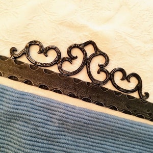 May include: A black metal wall hanging with a decorative design featuring a series of connected heart shapes.