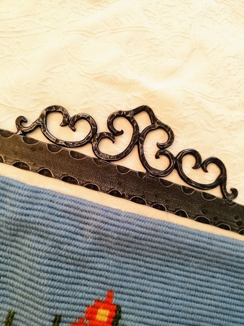 May include: A black metal wall hanging with a decorative design featuring a series of connected heart shapes.