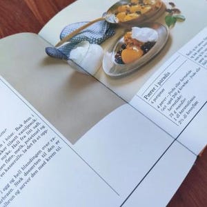 Puede incluir: Un libro de cocina abierto en una receta de peras en el para&iacute;so. La receta requiere 4 peras, 200 gramos de ricotta, 75 gramos de almendras, 100 ml de caramelo y 200 ml de nata.