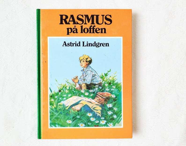Puede incluir: Un libro infantil vintage titulado "Rasmus p&aring; loften" de Astrid Lindgren. La portada presenta una ilustraci&oacute;n de dos ni&ntilde;os en un campo de flores. Un ni&ntilde;o est&aacute; sentado en el suelo, mientras que el otro est&aacute; acostado.